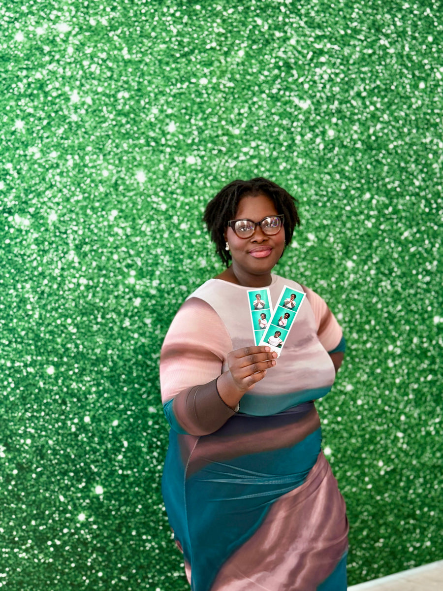 Guest holding photo strips against a green sparkle-effect printed backdrop
