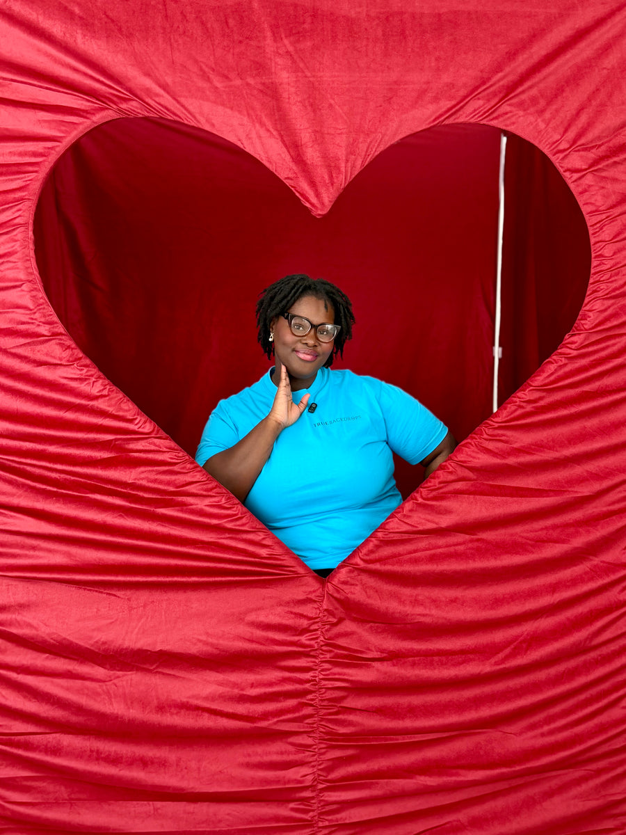Guest posing inside a red heart photo booth enclosure