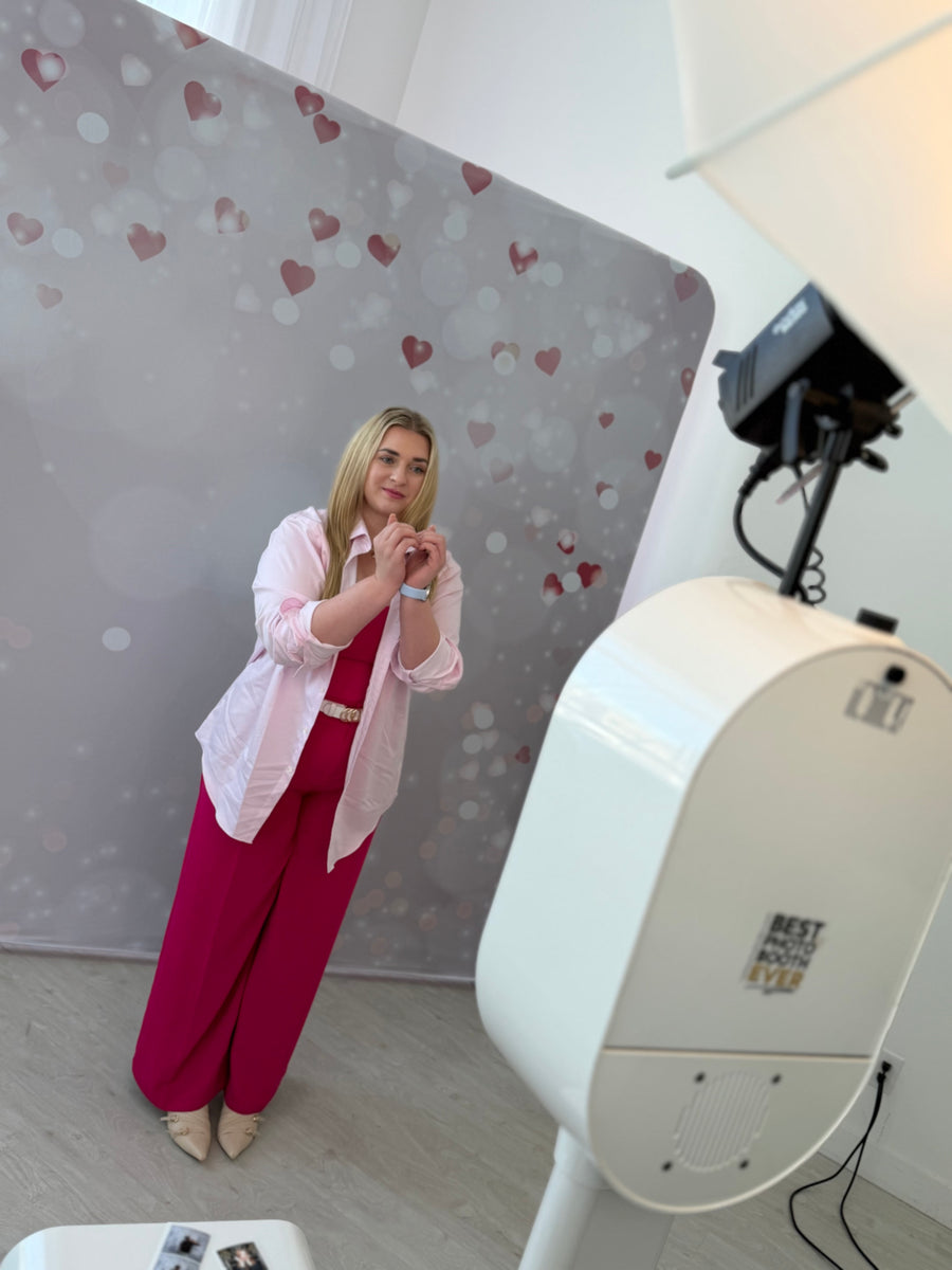 Guest using a photo booth in front of a soft pink printed pillowcover backdrop