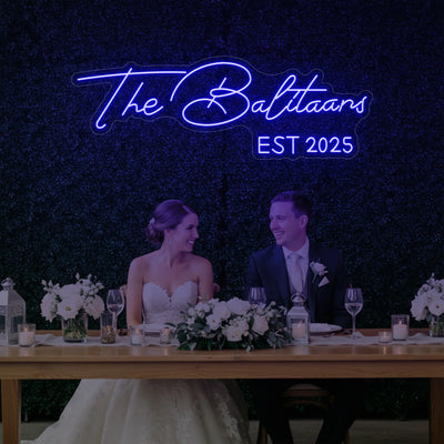Custom wedding neon sign with last names, illuminated in bright colors, designed for wedding décor by Light Your Way.