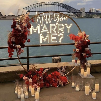 Light Your Way "Will You Marry Me?" neon sign glowing with bright, colorful lettering on a dark background.